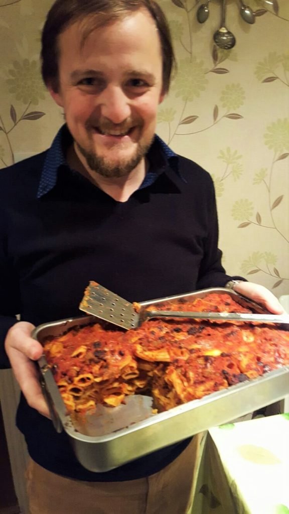 George holding a baking dish with pasta al forno